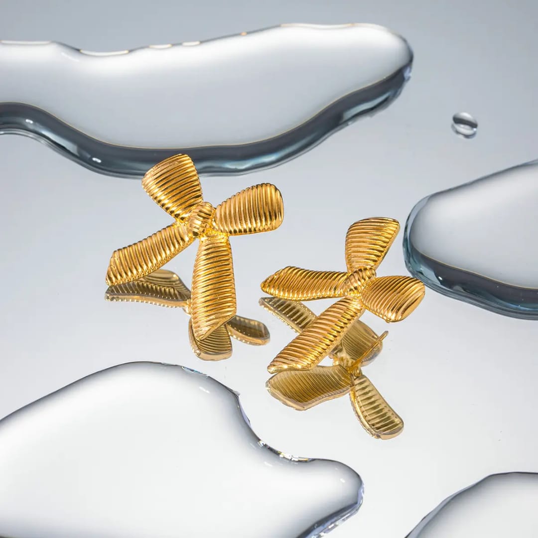 Gold earrings with a ribbed design on a reflective surface